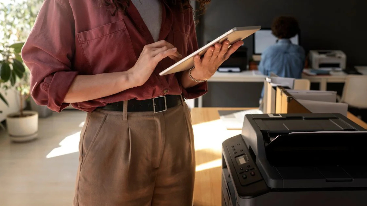 side-view-woman-holding-tablet-near-printer